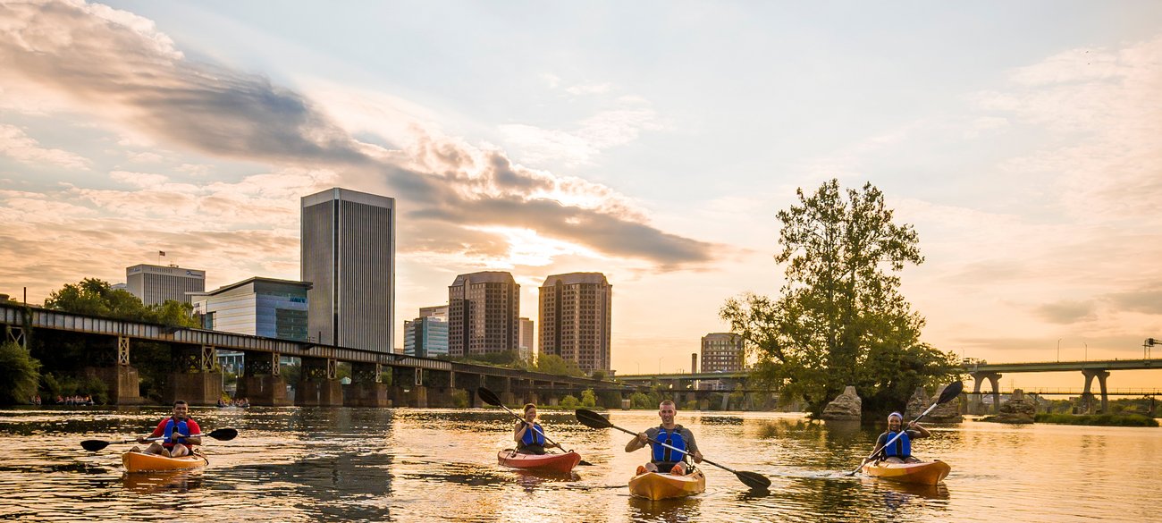 View of people kayaking with skyline at sunset during a Richmond Flight + Hotel JetBlue Vacations package