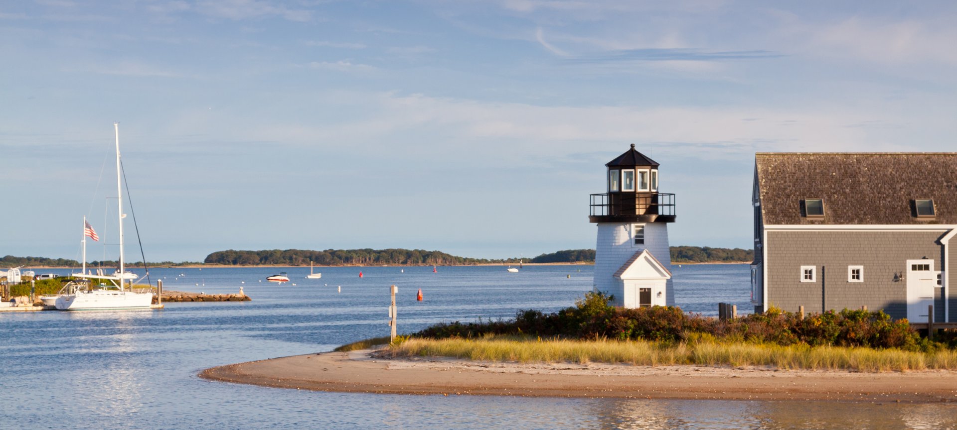 View of lighthouse and sailboat on a Hyannis, Massachusetts Flight + Hotel all inclusive JetBlue Vacations package