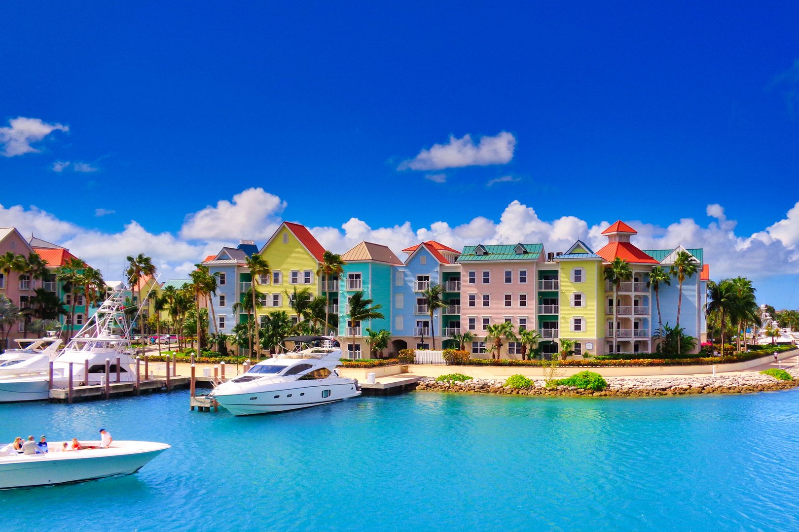 View of boats, beach and architecture from water on Nassau, Bahamas with a Flight + Hotel Vacation Package