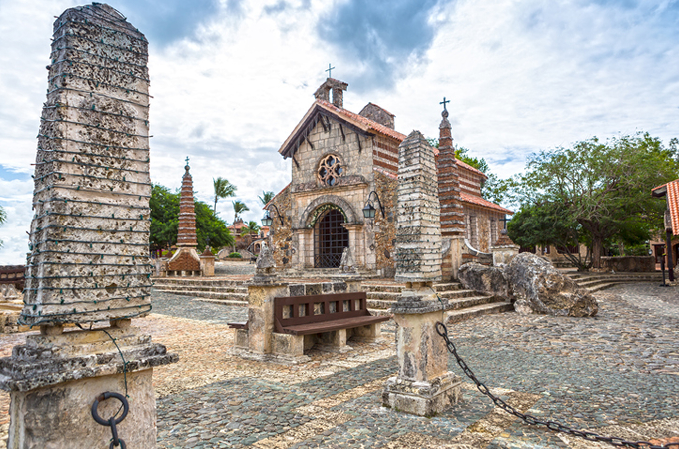 Stone-built chapel and courtyard at the Altos de Chavón cultural village in the Dominican Republic, featuring cobblestone paths, ornate columns and tropical foliage
