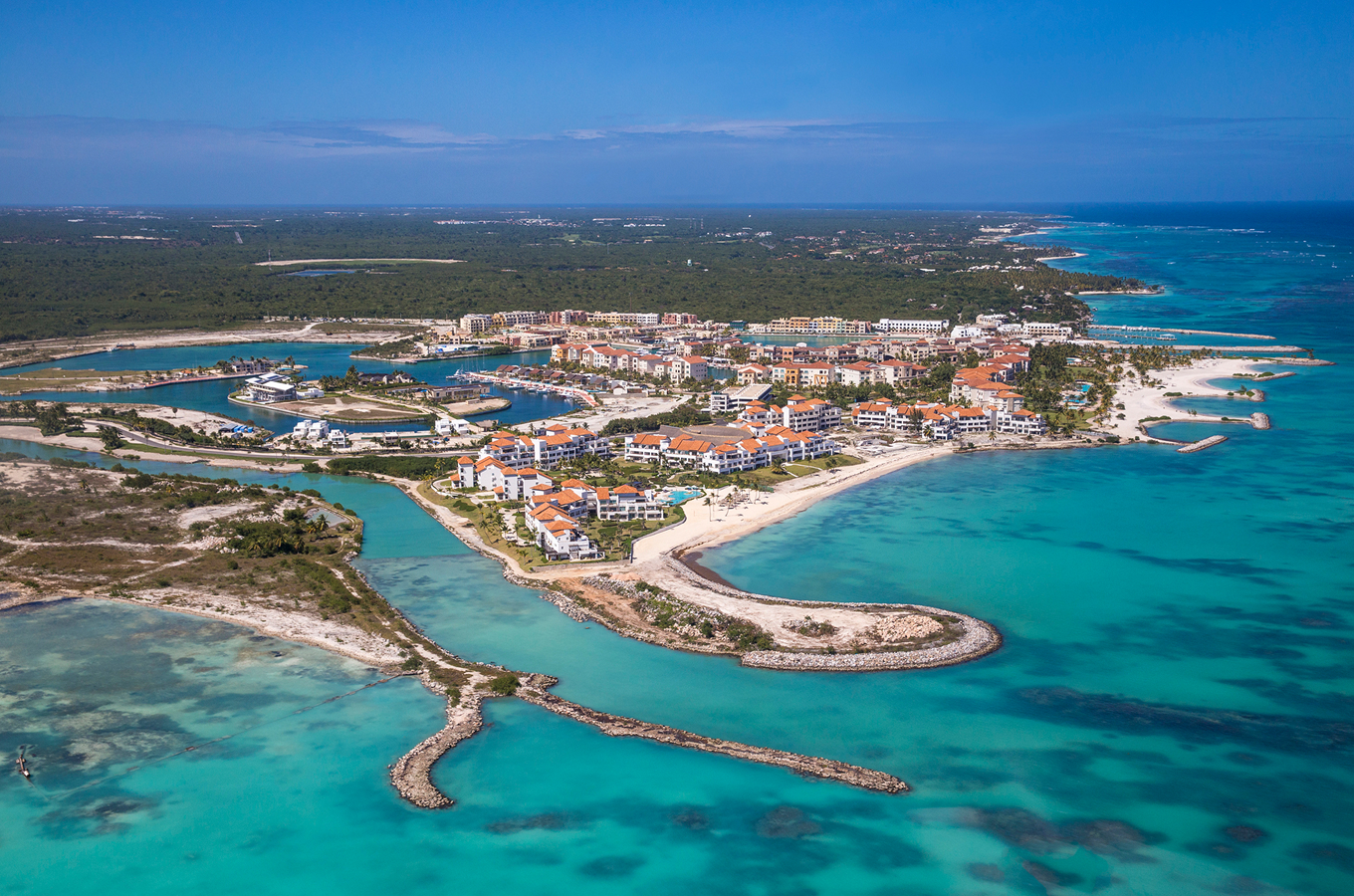 Aerial view of Cap Cana in Punta Cana, Dominican Republic, featuring turquoise bays, white-sand beaches, marina docks and resort buildings clustered along the coastline