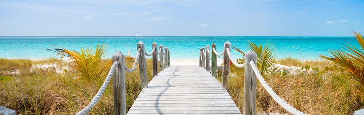 View of boardwalk through foliage to beach on a JetBlue Vacation all inclusive package